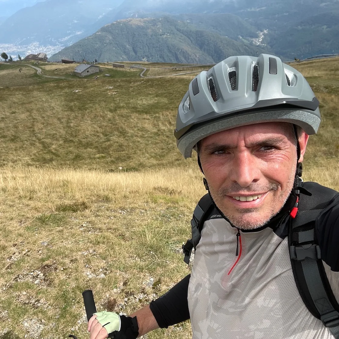 Massimo in bicicletta su un alpe, con la valle sullo sfondo